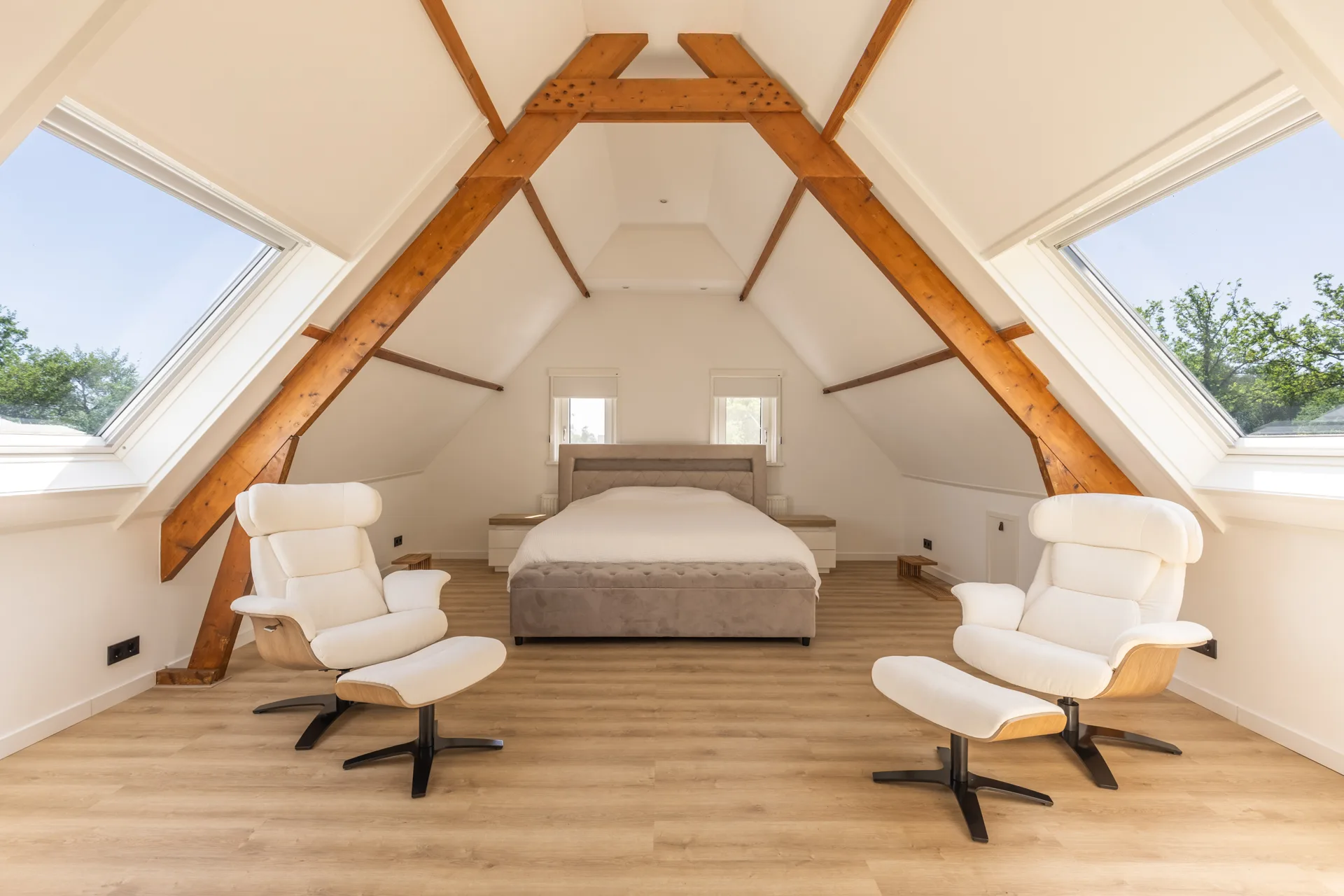 Ruime zolderslaapkamer met houten kapbalken en dakramen, interieur vastgoedfotografie